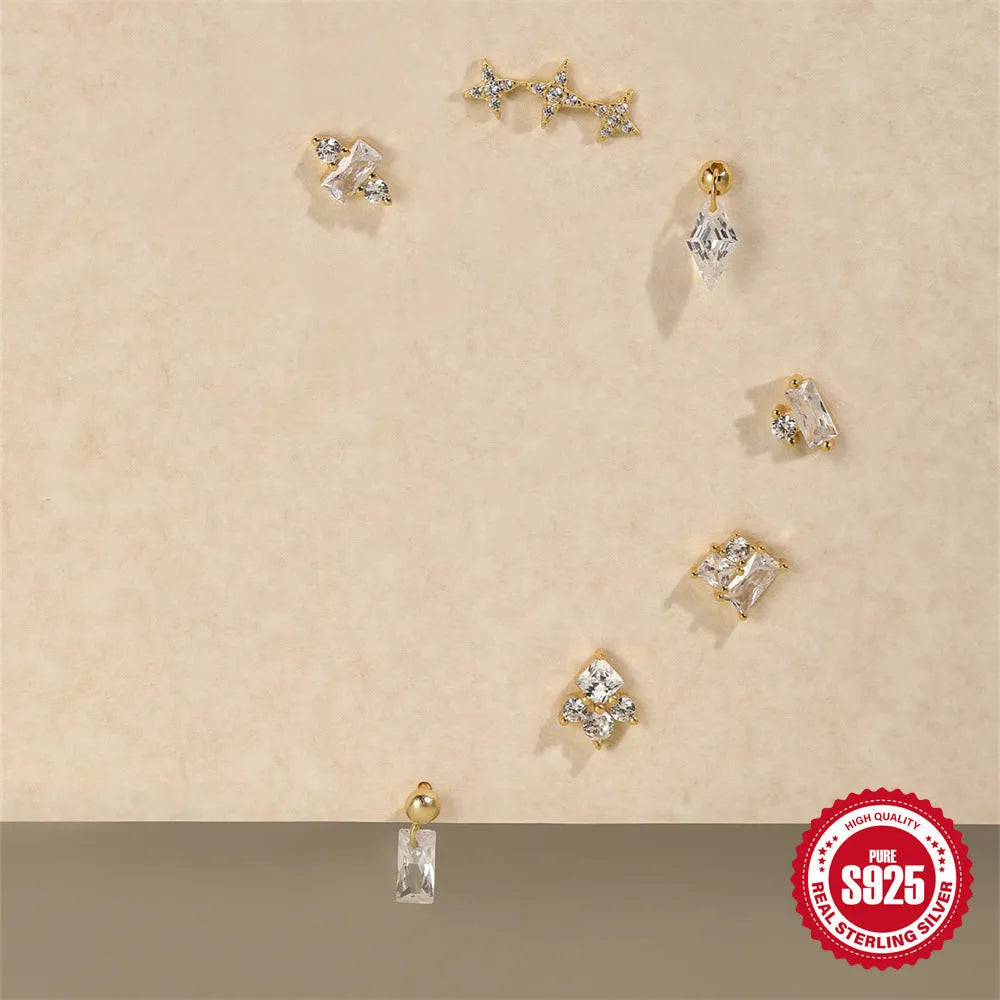 Close-up of women's flower-shaped sterling silver stud earrings with red square gravel stones and a gold electroplated finish.
