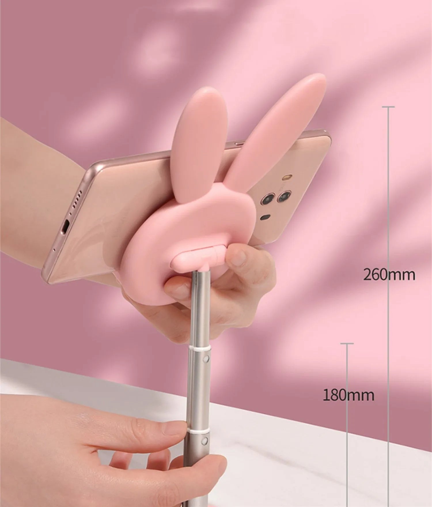 Rabbit-shaped silicone phone stand in pink on a desk with a mobile phone