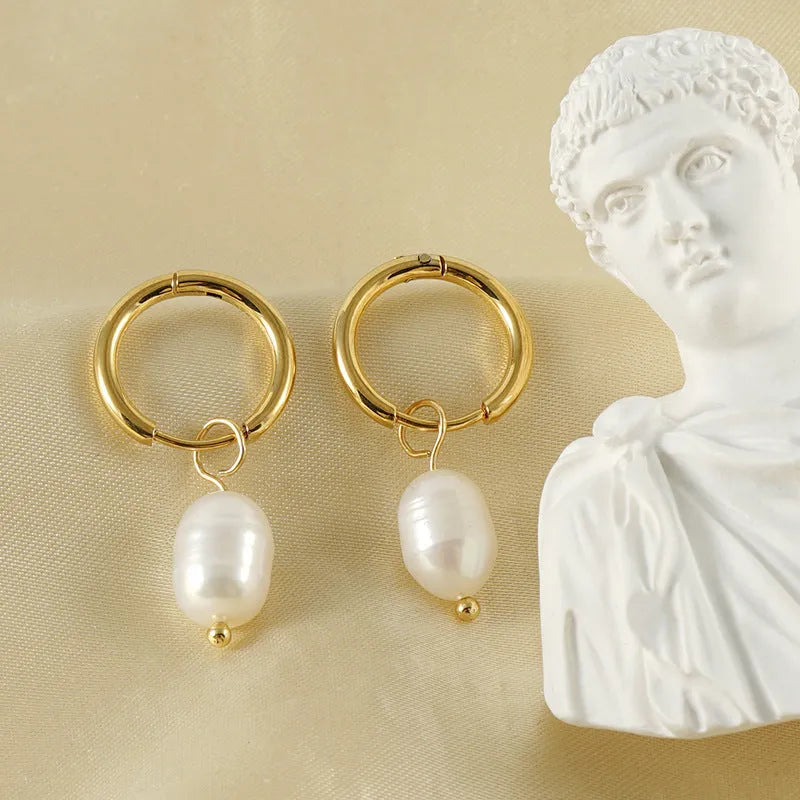 A pair of gold geometric drop earrings featuring stainless steel construction and central freshwater pearls.