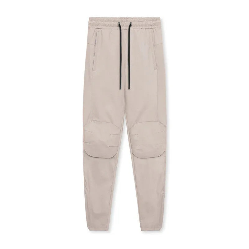 Man wearing dark grey loose-fit fitness trousers with tied ankle cuffs, made from quick-dry polyester fabric.