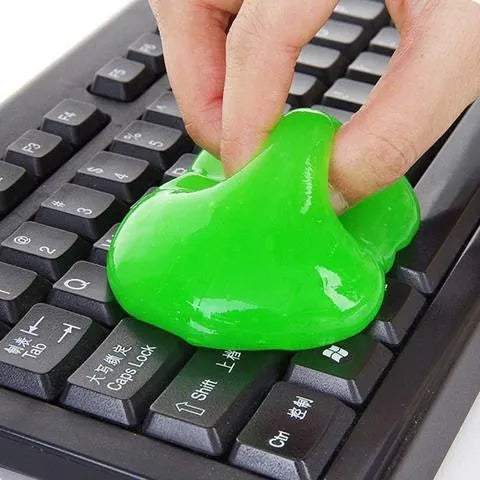 Blue magic cleaning gel putty being pressed onto a laptop keyboard to remove dust.