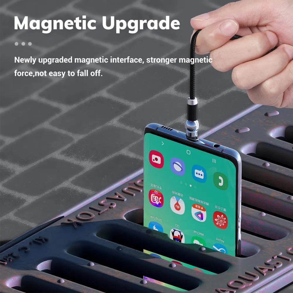 Black magnetic charging cable with spherical rotating connector next to a mobile phone.