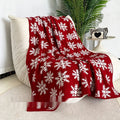 Red and white Christmas blanket with cartoon reindeer pattern on a sofa