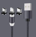 Black magnetic charging cable with spherical rotating connector next to a mobile phone.