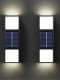 White solar wall lamp with bidirectional sensor mounted on a brick wall, showing warm light illumination