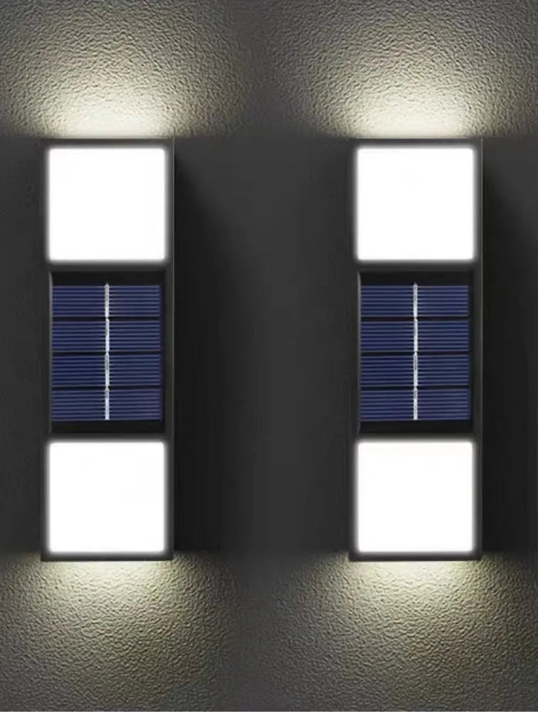White solar wall lamp with bidirectional sensor mounted on a brick wall, showing warm light illumination