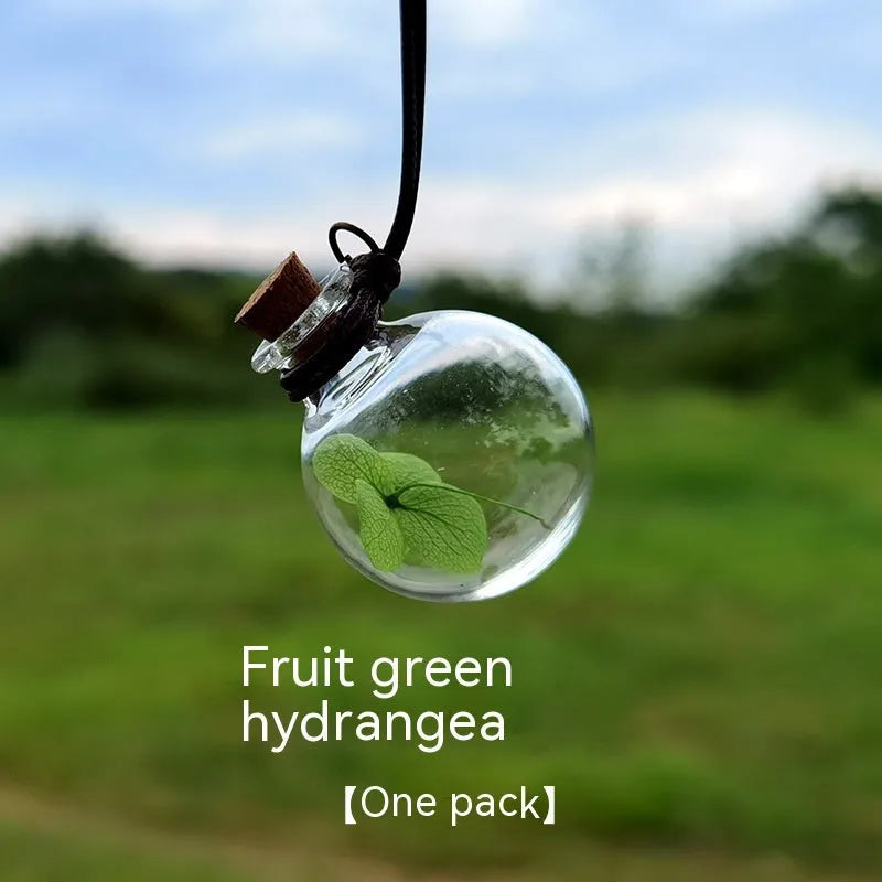 Glass car perfume pendant with preserved flowers inside, shown in a selection of different floral colours.