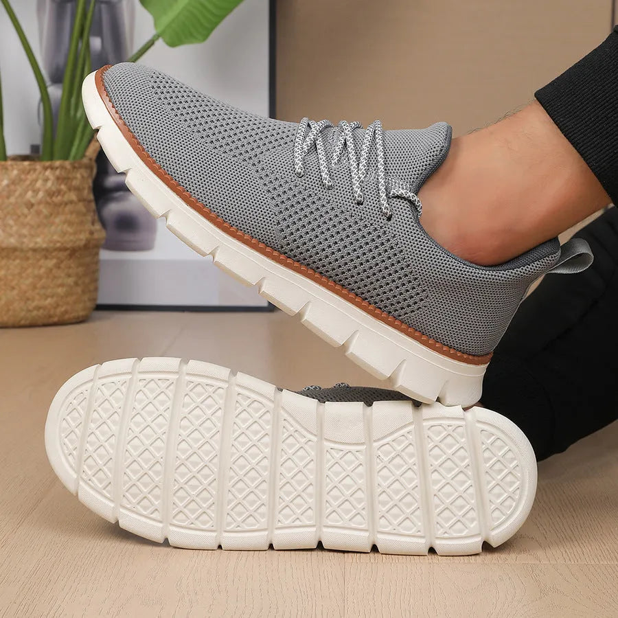 Men's grey and black mesh fabric casual sneakers with a round toe and low heel on a plain background.