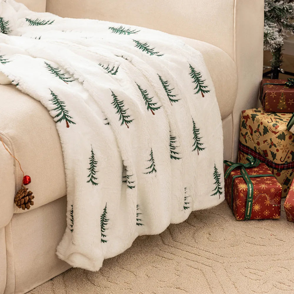 White plush sofa blanket with embroidered Christmas tree design on a sofa
