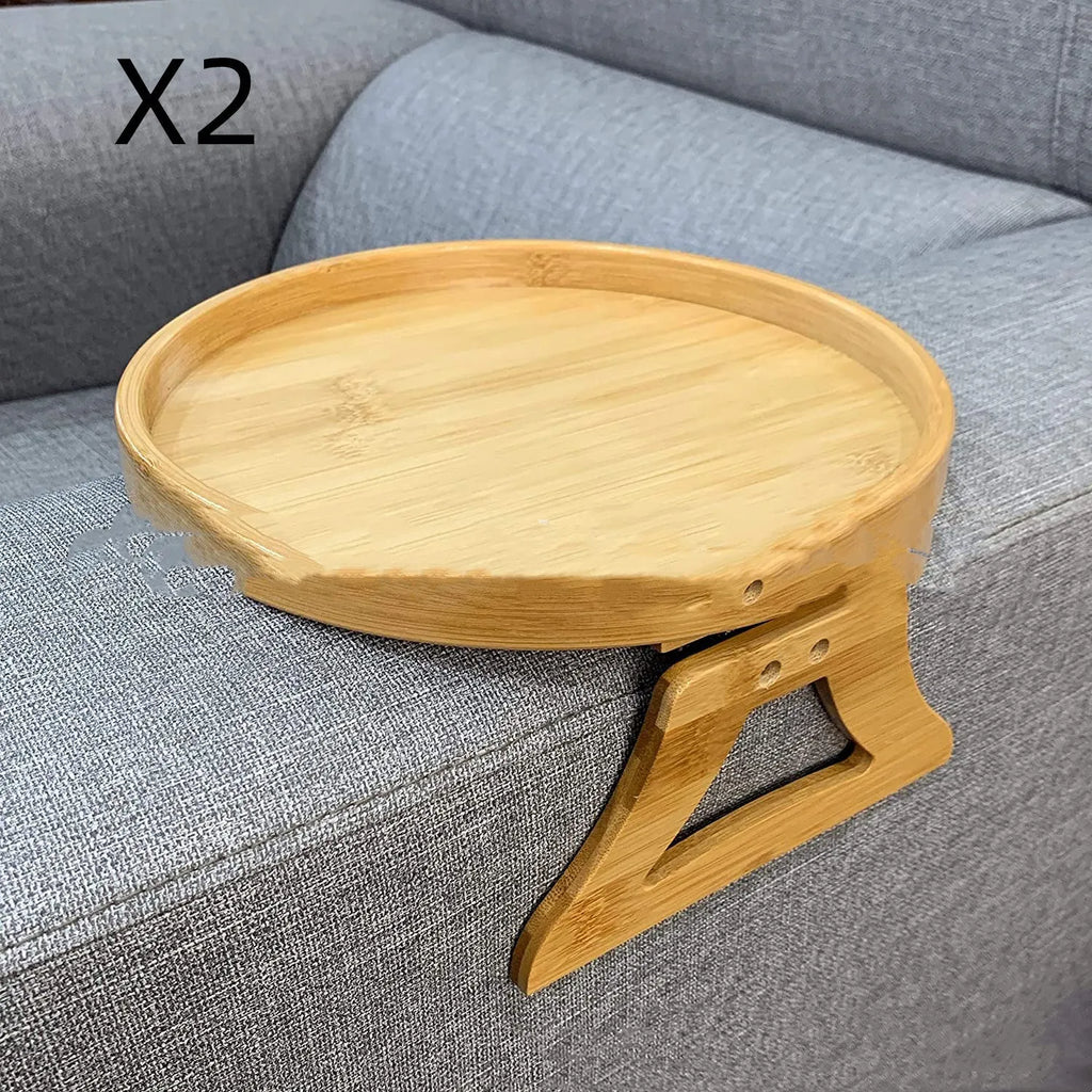 Wooden clip-on sofa tray table with carved surface in bamboo colour, attached to armrest holding snacks and remote