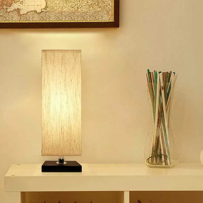 Modern simple square cloth covered table lamp 110V with E26 socket and off-white fabric shade on a desk