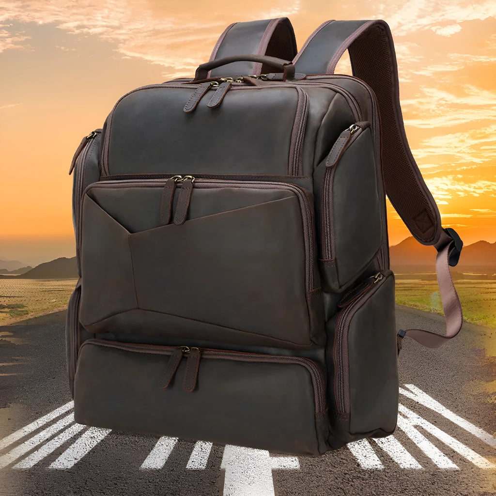 Dark brown men's leather backpack open to show internal compartments for a 17-inch laptop and organisation pockets.