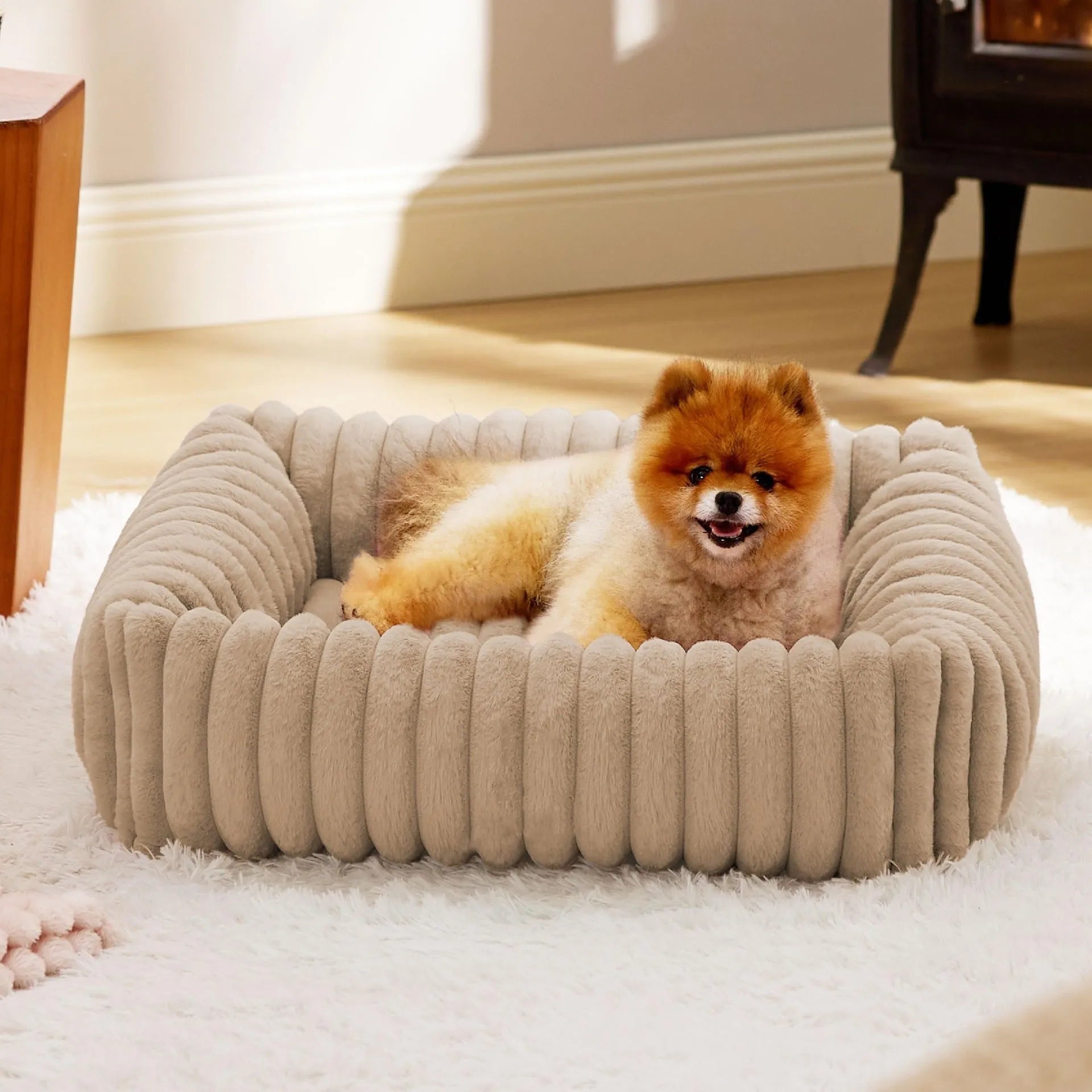 Beige raised cushion pet bed for a medium-sized dog on a wooden floor.