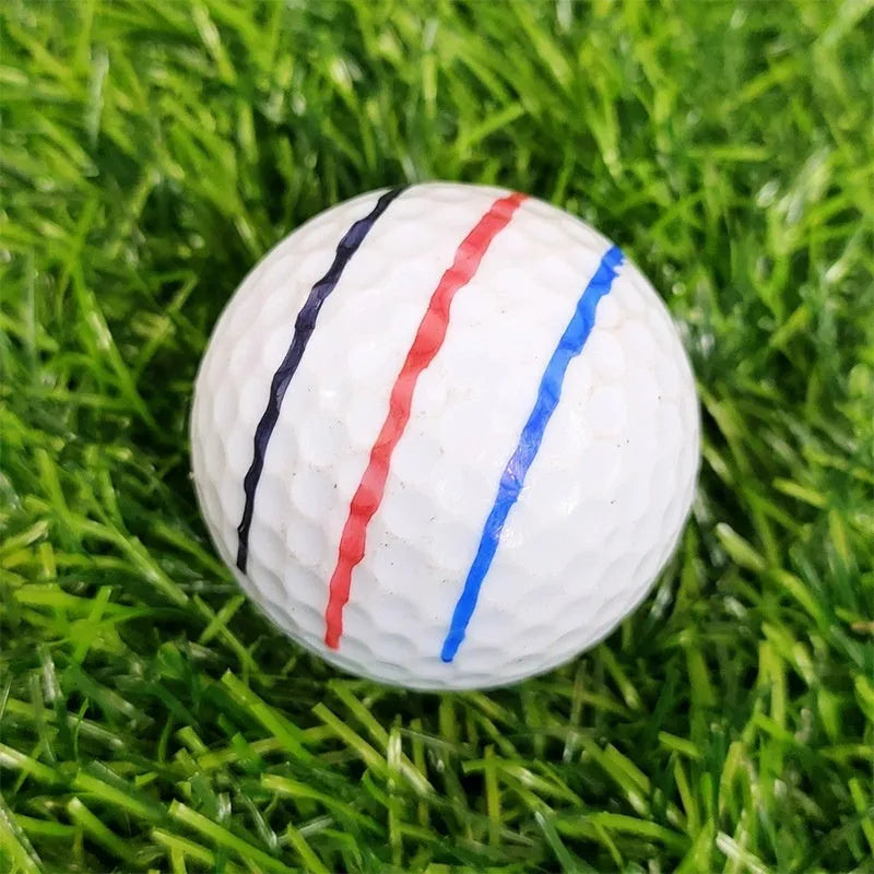 White golf ball alignment tool with four black adjustable scriber arms and a blue drawing pen on a green.