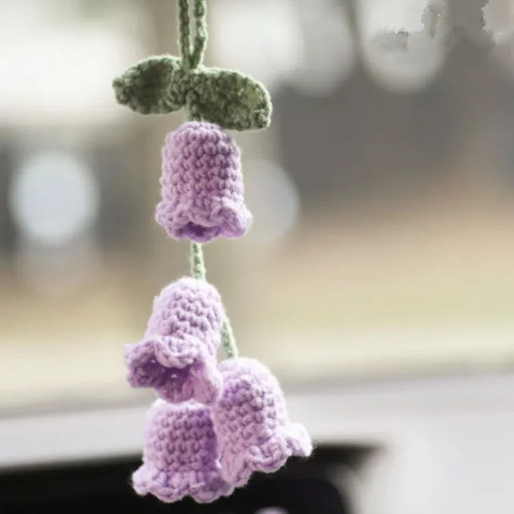 Green and white crocheted wool car plant decoration with a white hanging rope.
