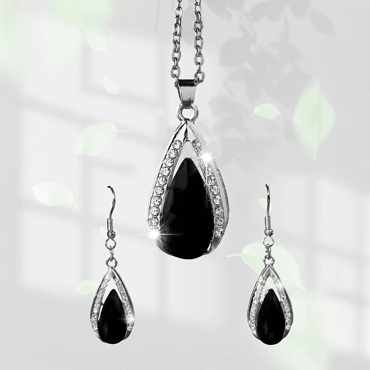 Black and red teardrop-shaped glass pendant necklace and matching earrings set laid flat.
