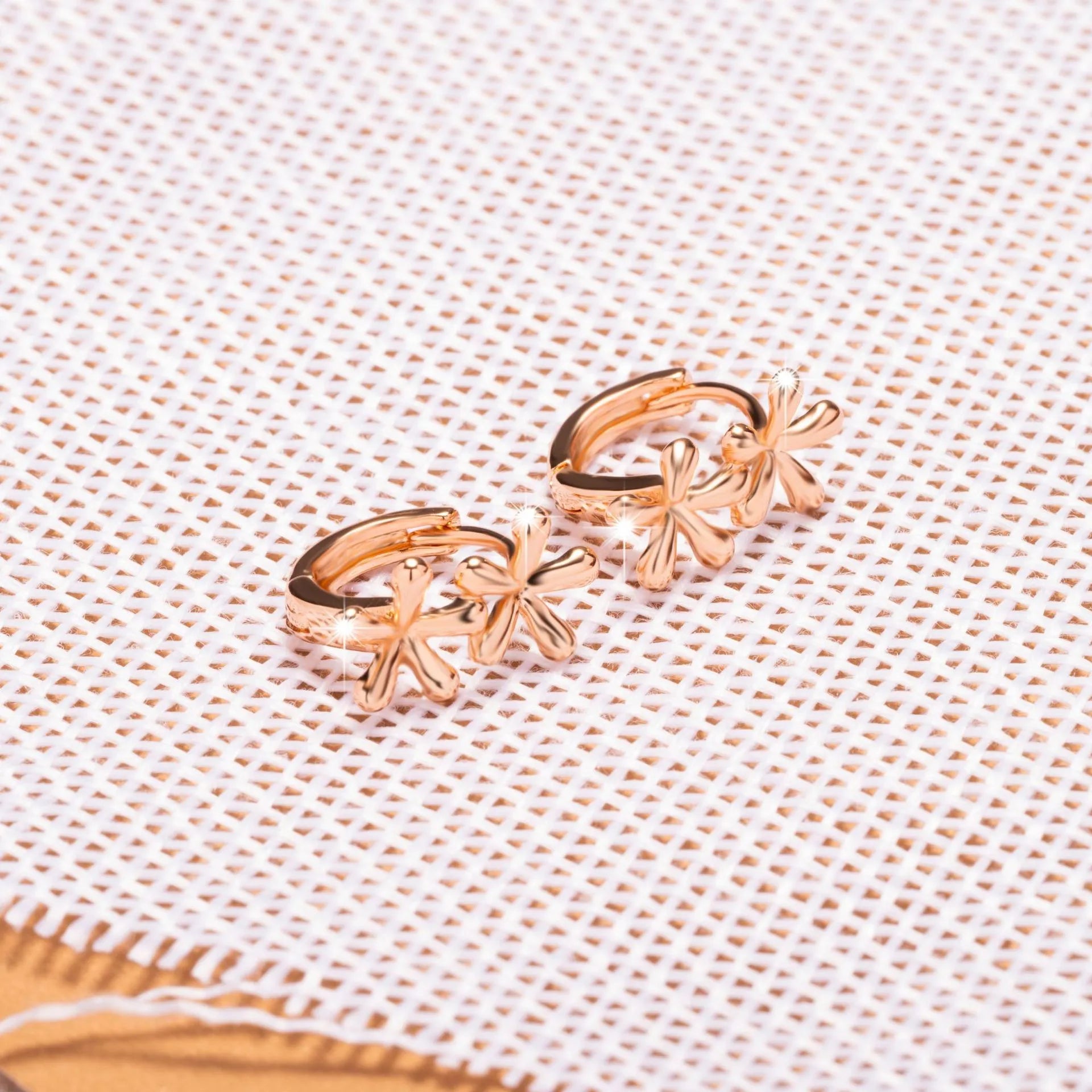 Rose gold circular waterdrop flower earrings with sterling silver posts on a white background.