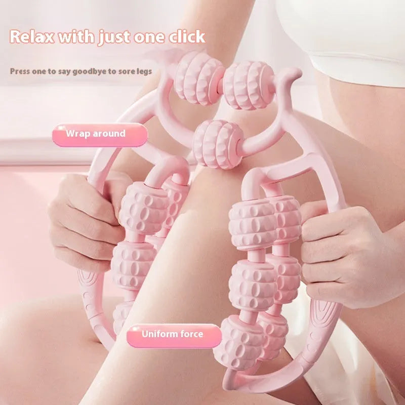 A small, handheld leg massage roller with double-row wheels in coral pink, shown on a table.