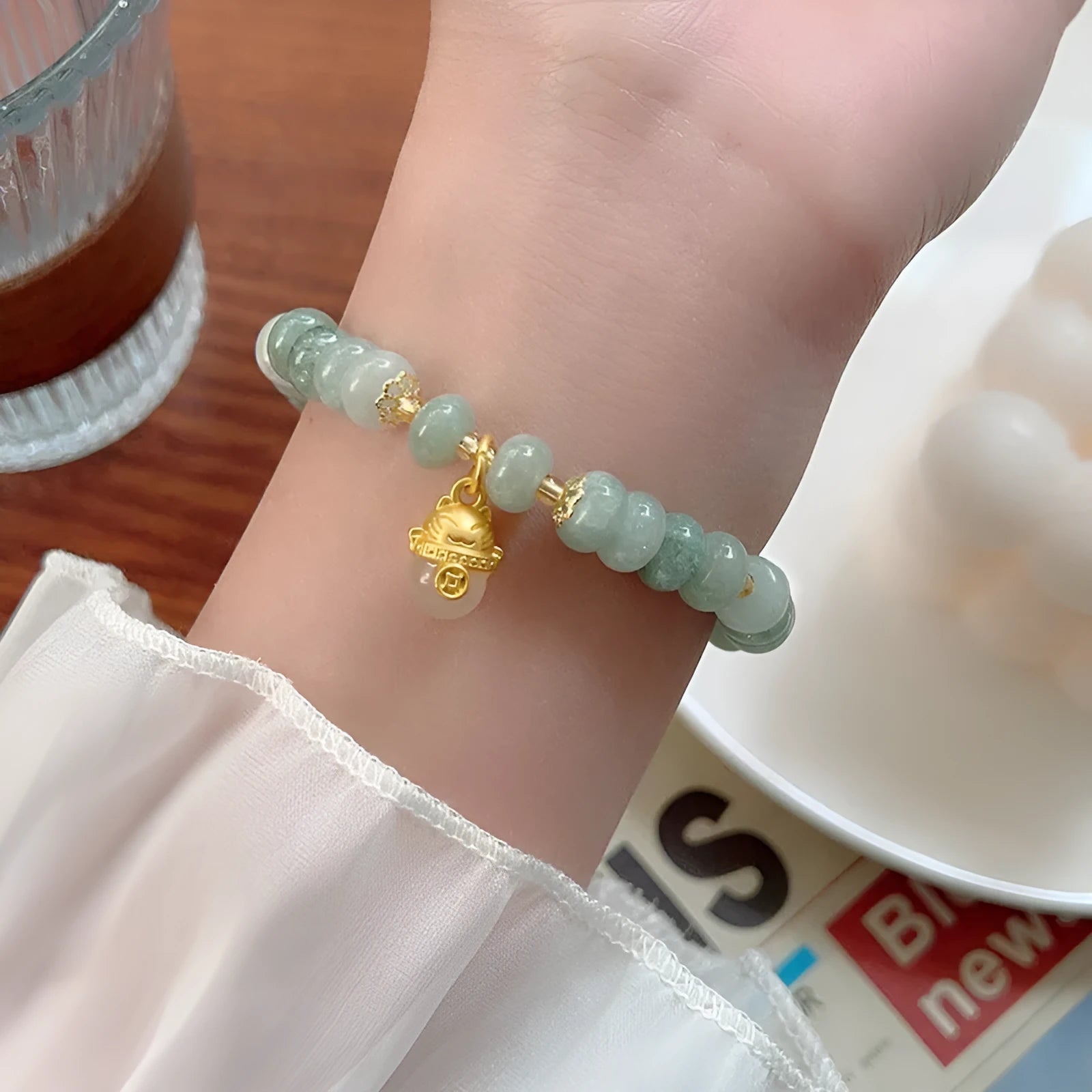 Women's strawberry quartz bracelet with lucky cat charm on grey background