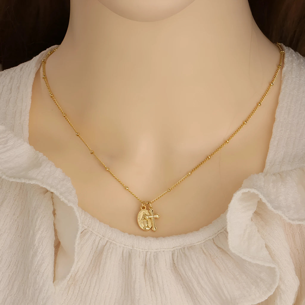 Geometric gold cross Virgin Mary pendant necklace on a chain with a lobster clasp.