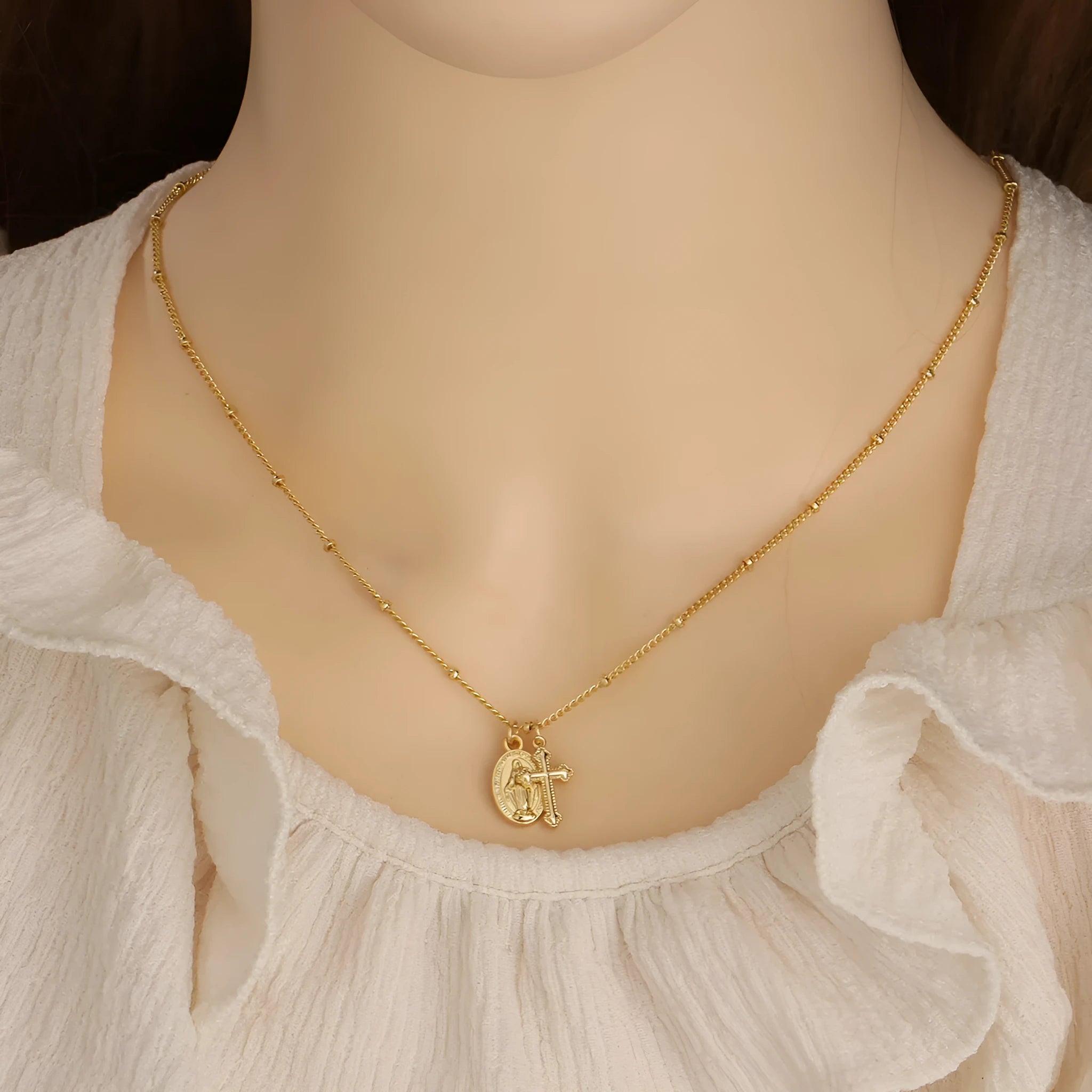 Geometric gold cross Virgin Mary pendant necklace on a chain with a lobster clasp.
