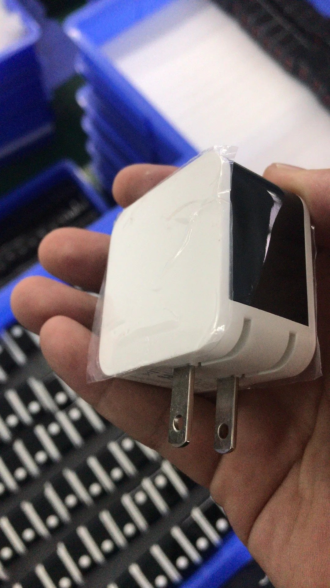 Black dual USB fast charger with digital display showing voltage and current, next to UK plug