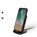 Dark grey vertical wireless charging stand for Apple iPhones on a desk