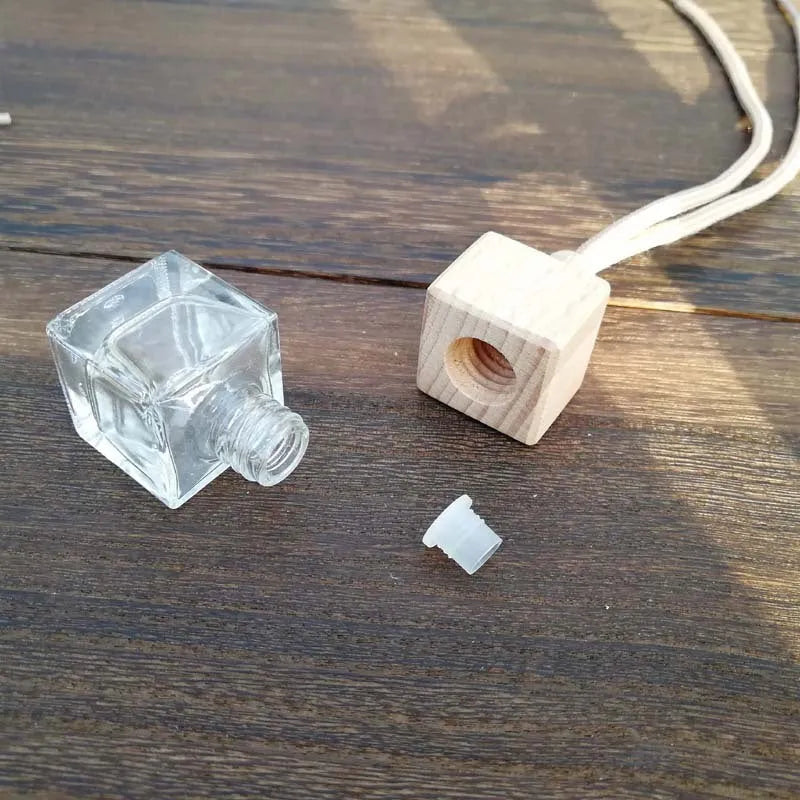 Square clear glass car fragrance pendant bottle with 8ml capacity hanging from a rearview mirror