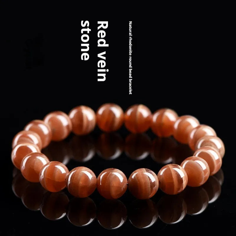Natural Old Mine Rhodochrosite mineral bracelet with round beads in 6mm or 8mm size on a wrist.