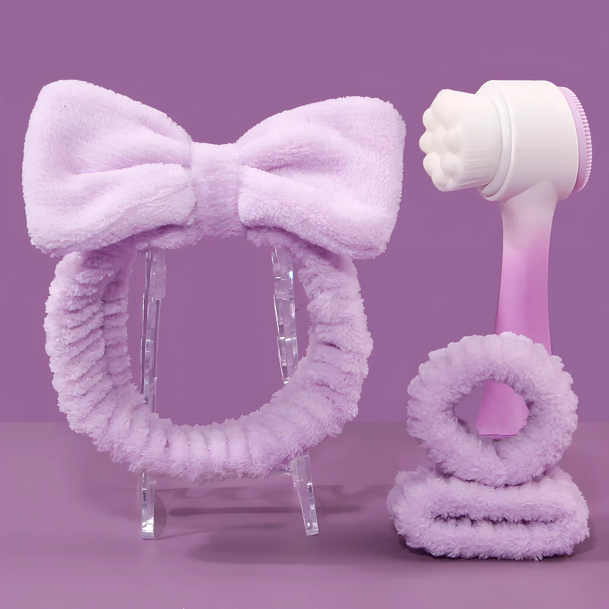Three-piece facial skincare set showing a nylon brush and a coral fleece hair band in purple.