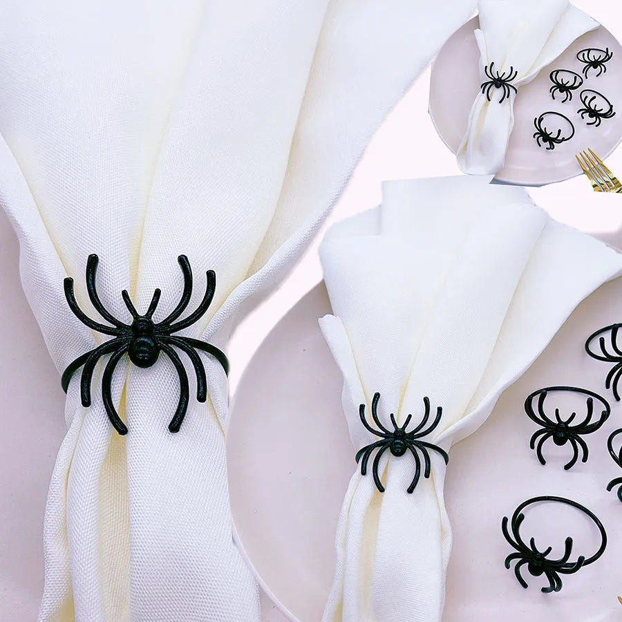 Set of six black alloy spider-shaped napkin rings on a dark tablecloth.
