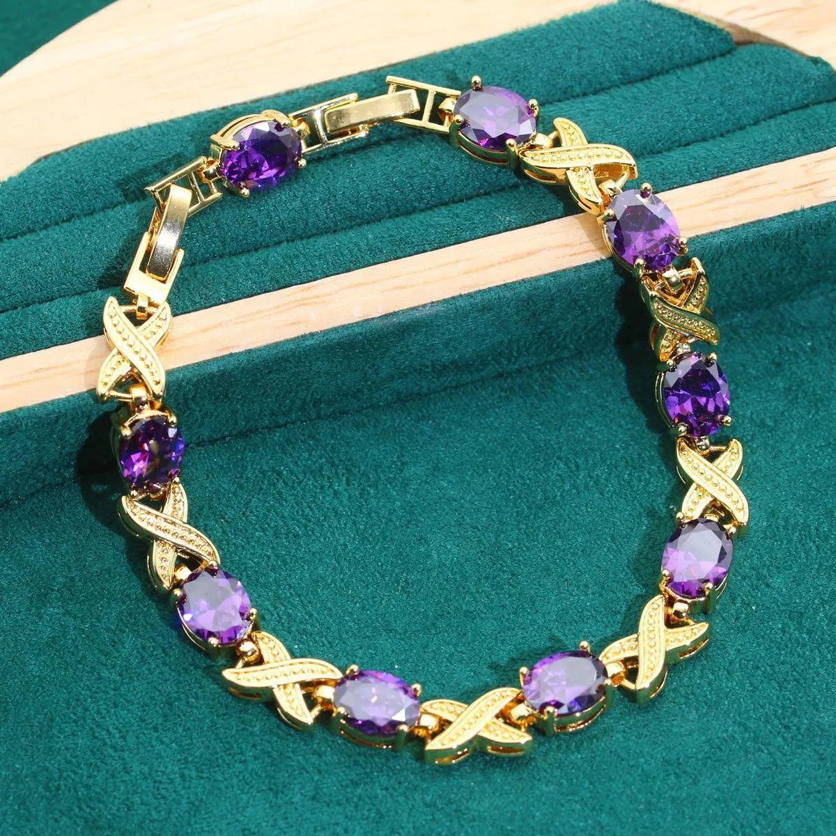 Gold jewellery set with sparkling blue cubic zirconia stones, showing necklace, earrings, ring, and bracelet on a dark background.