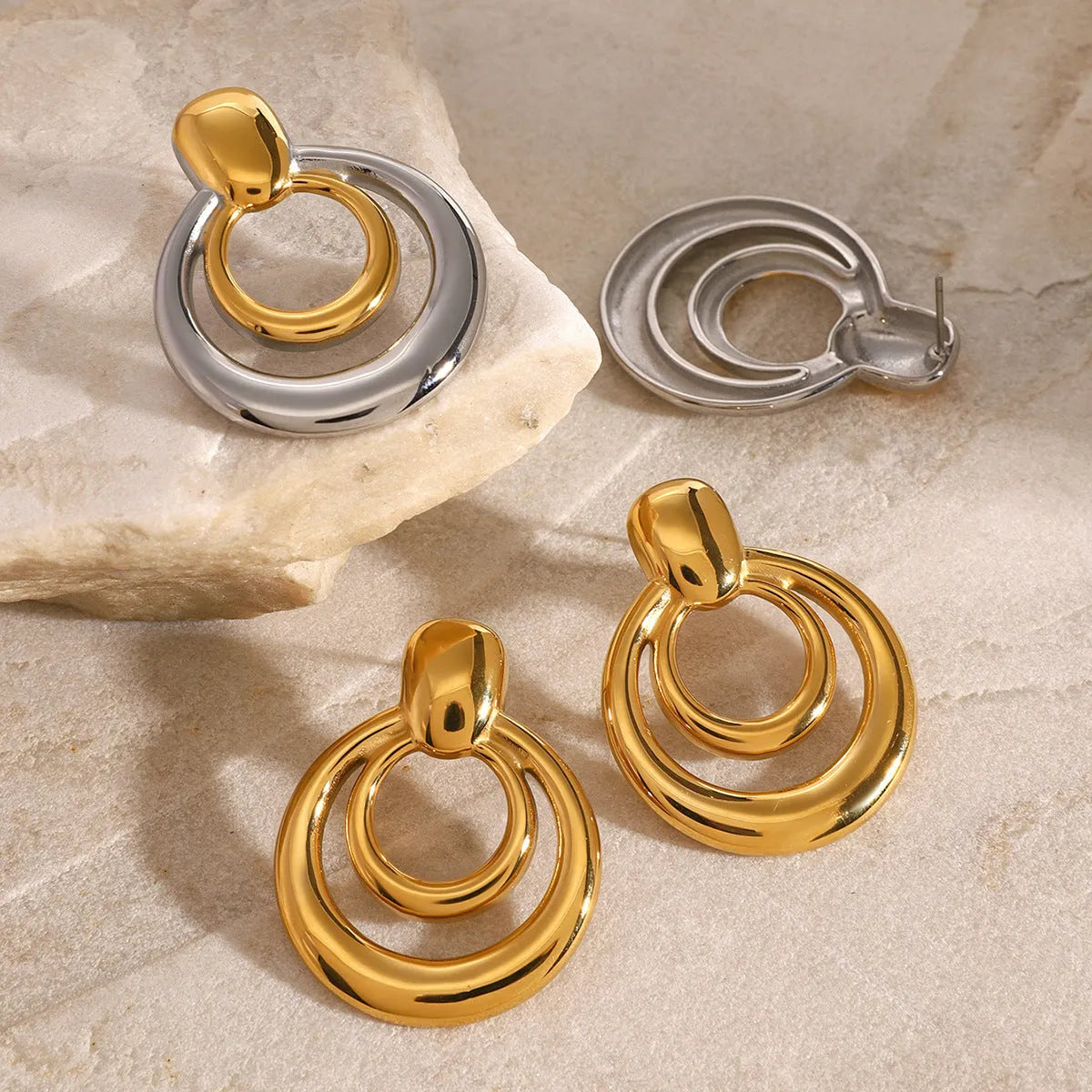 Round golden double layer hollow stud earrings with a geometric design on a white background.