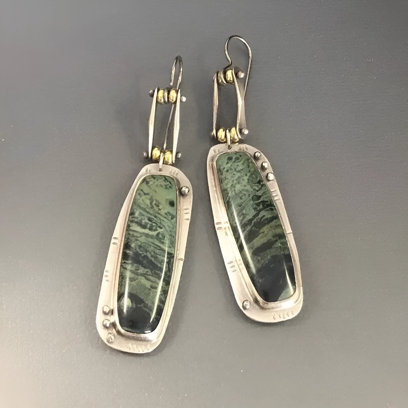 Geometric alloy earrings with a two-colour marble pattern on a white background.