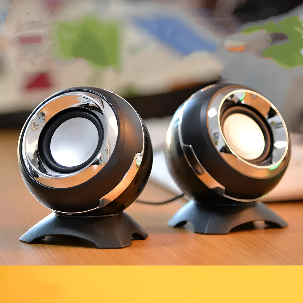 USB-powered computer stereo speakers in black gold and white gold metallic finishes beside laptop