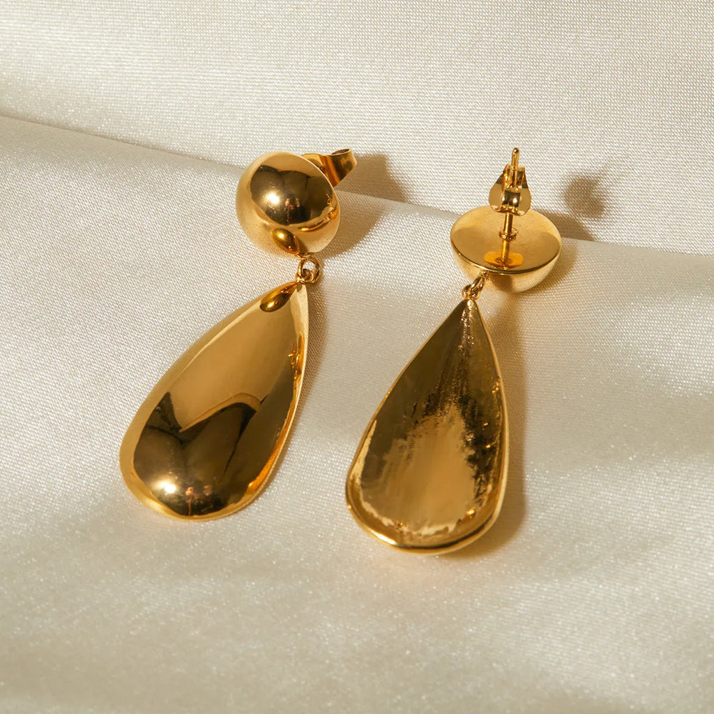 A pair of gold-coloured geometric hemisphere earrings with a hanging water droplet pendant.