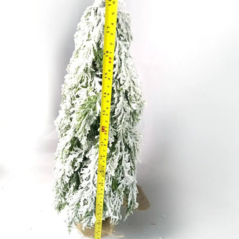 Small 24-inch white artificial Christmas tree with LED lights and snow effect on a desktop