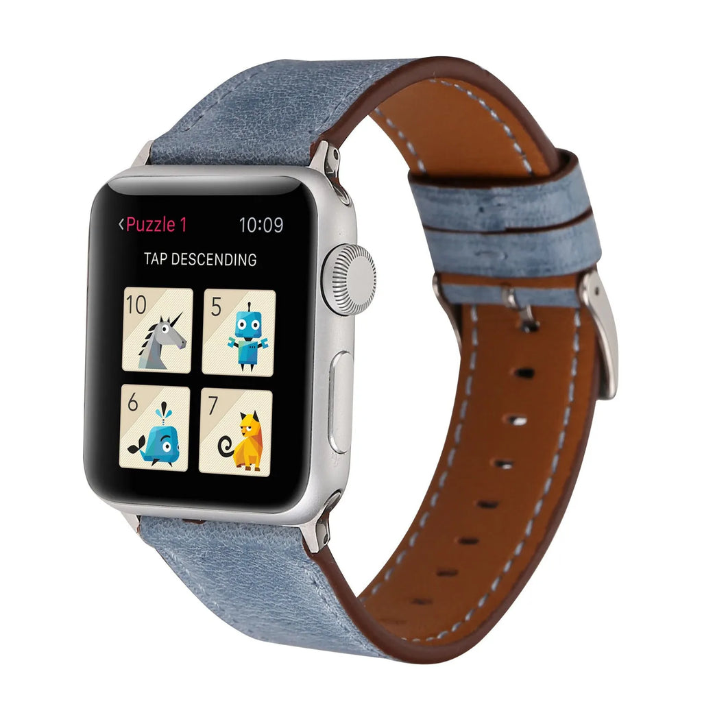 Leather watch strap with a metal folding buckle on a wooden surface.