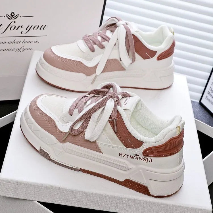 Beige children's platform trainers with cross shoulder straps and white rubber soles on a wooden floor.