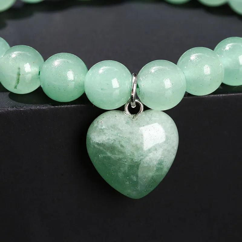 Natural crystal Tigereye love pendant bracelet with heart geometric design on woman's wrist.