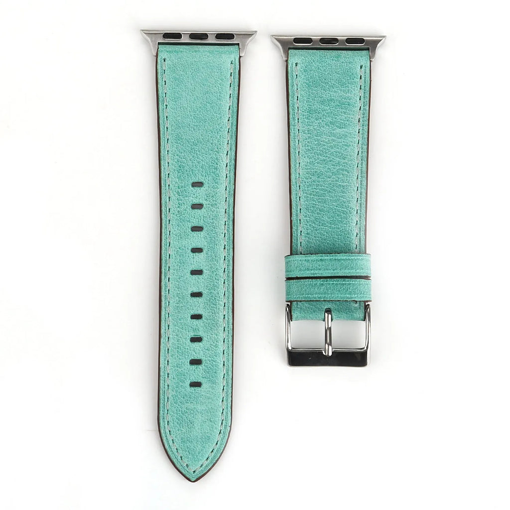 Leather watch strap with a metal folding buckle on a wooden surface.