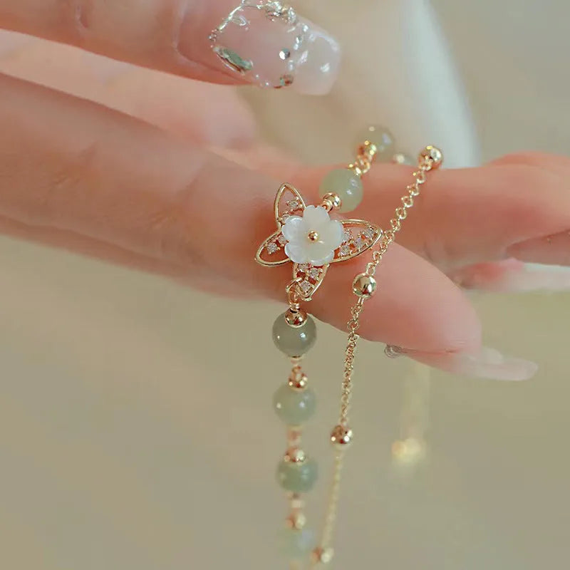 Yellow gold electroplated butterfly bracelet with shell flower design and Hetian jade accents on geometric copper jewellery