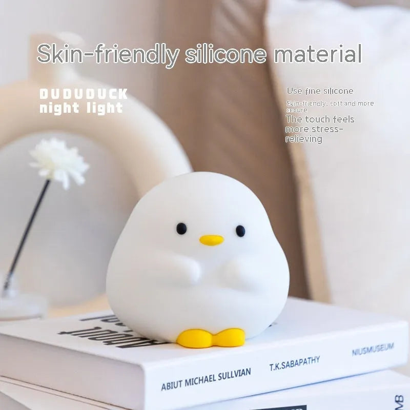 Cute duck-shaped silicone LED night lamp with touch sensor and warm glow on a bedside table