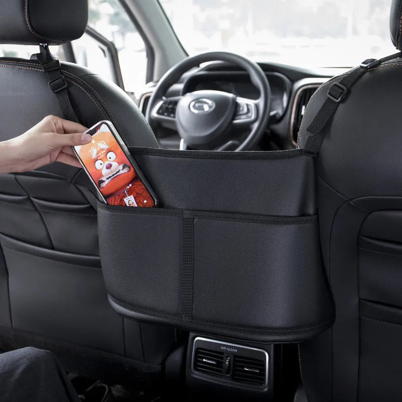 Black leather car seat storage bag with a carbon fibre pattern, shown in a vehicle seat gap.