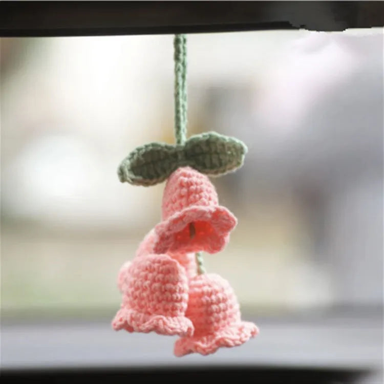 Green and white crocheted wool car plant decoration with a white hanging rope.