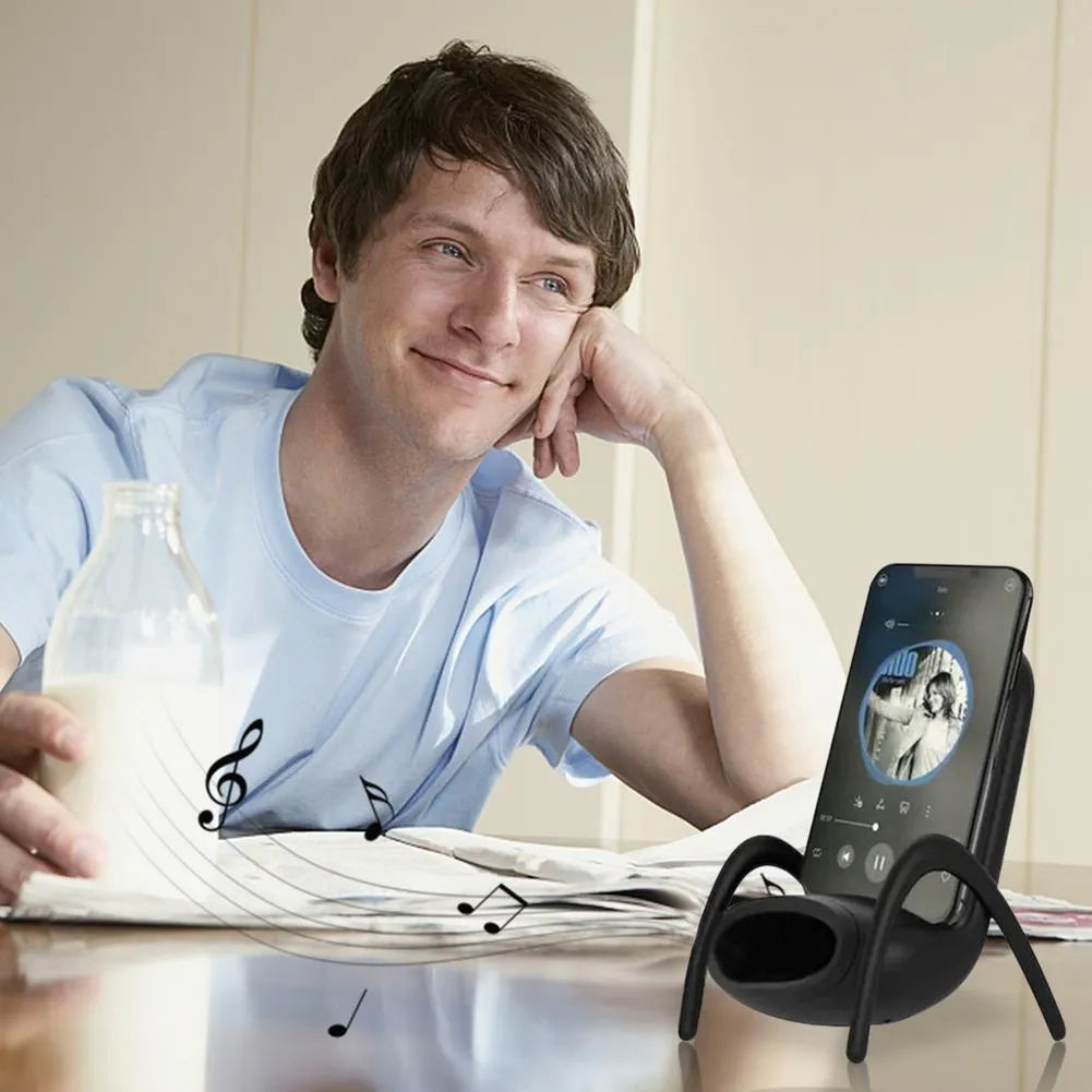 White mini chair-shaped wireless phone charger on a desk, with phone seated on it.