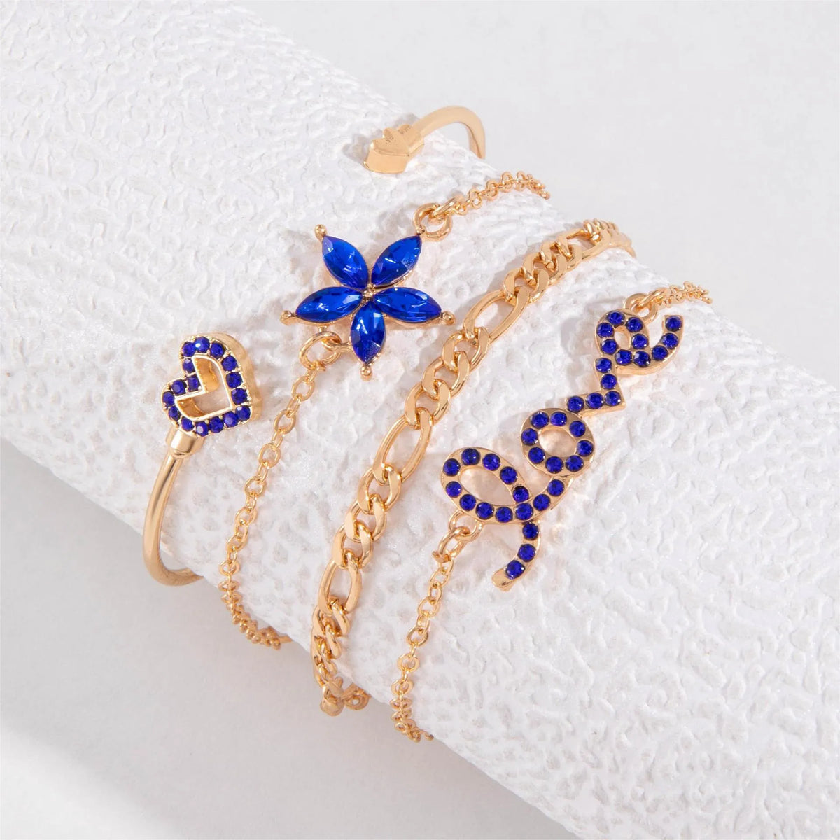Four-piece blue and gold-tone bracelet set with heart, butterfly, and flower designs, rhinestone accents, alloy electroplated finish