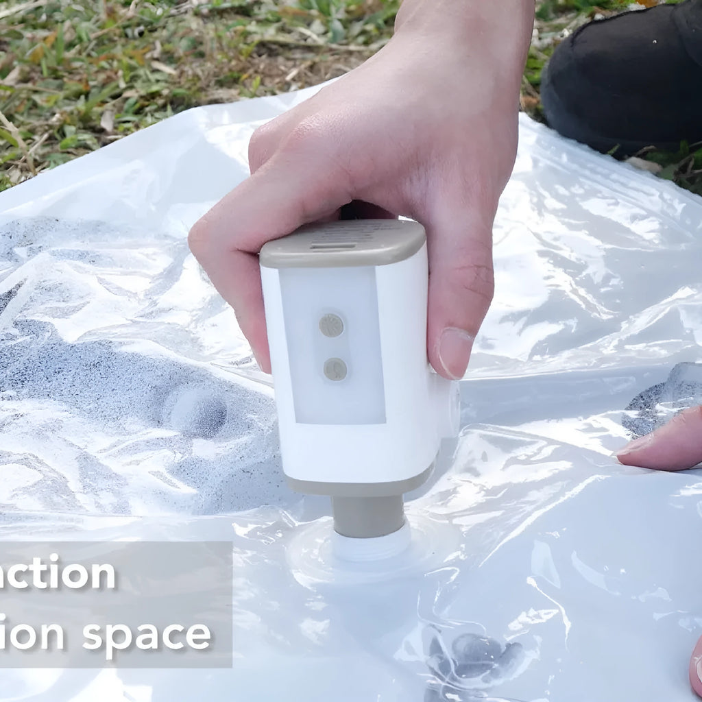 Portable mini motor pump in khaki white with USB cable and three air nozzles on a camping table