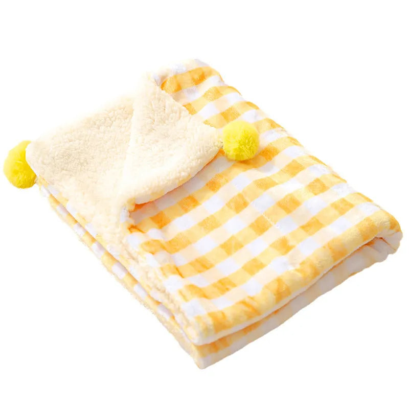 Blue coral fleece pet blanket folded next to a sleeping dog on a sofa.
