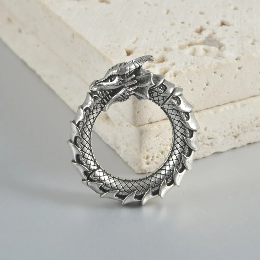 A pair of large, geometric dragon-shaped alloy earrings with an antique silver finish and hollow-out details.